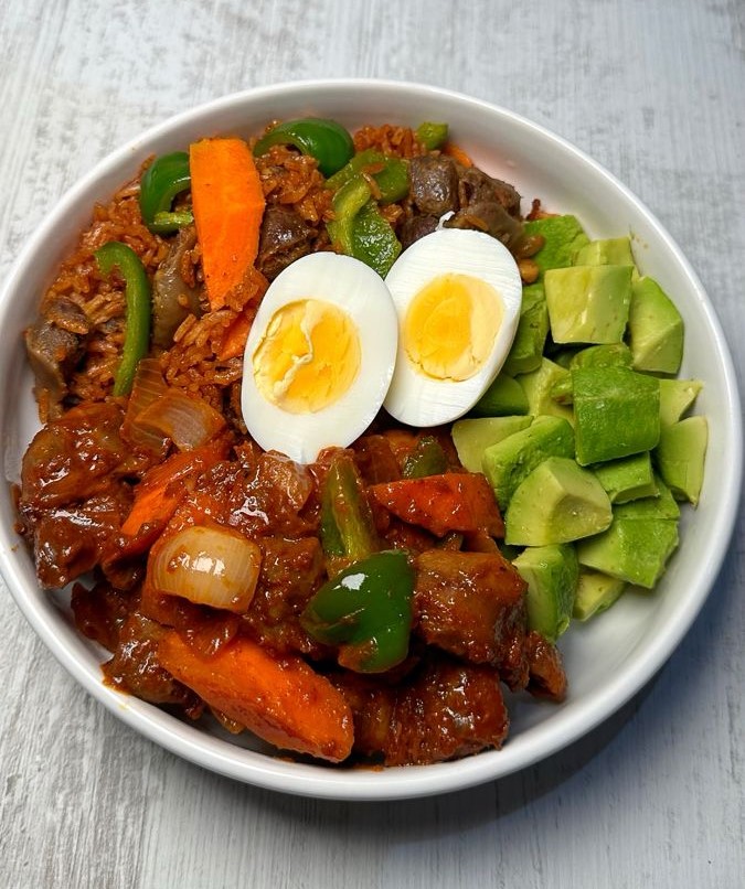 Nigerian jollof rice bowl with peppered beef, boiled egg and avocado